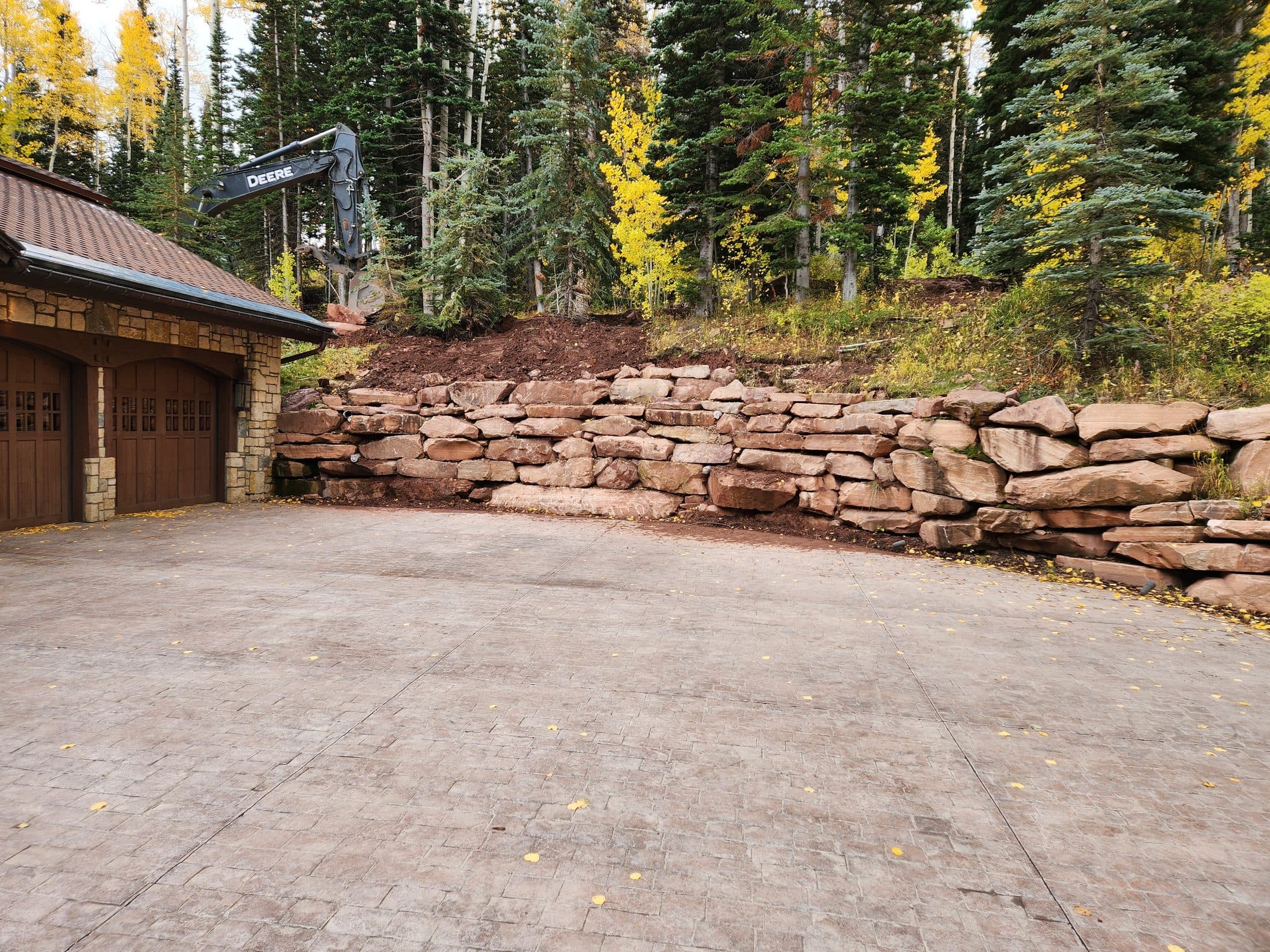 Rock retaining wall beside a wooded mountain home.